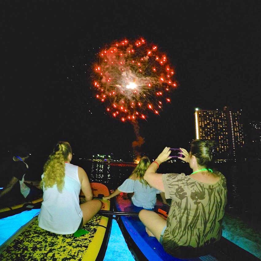Night paddle boarding with fireworks off Waikiki Beach, Oahu